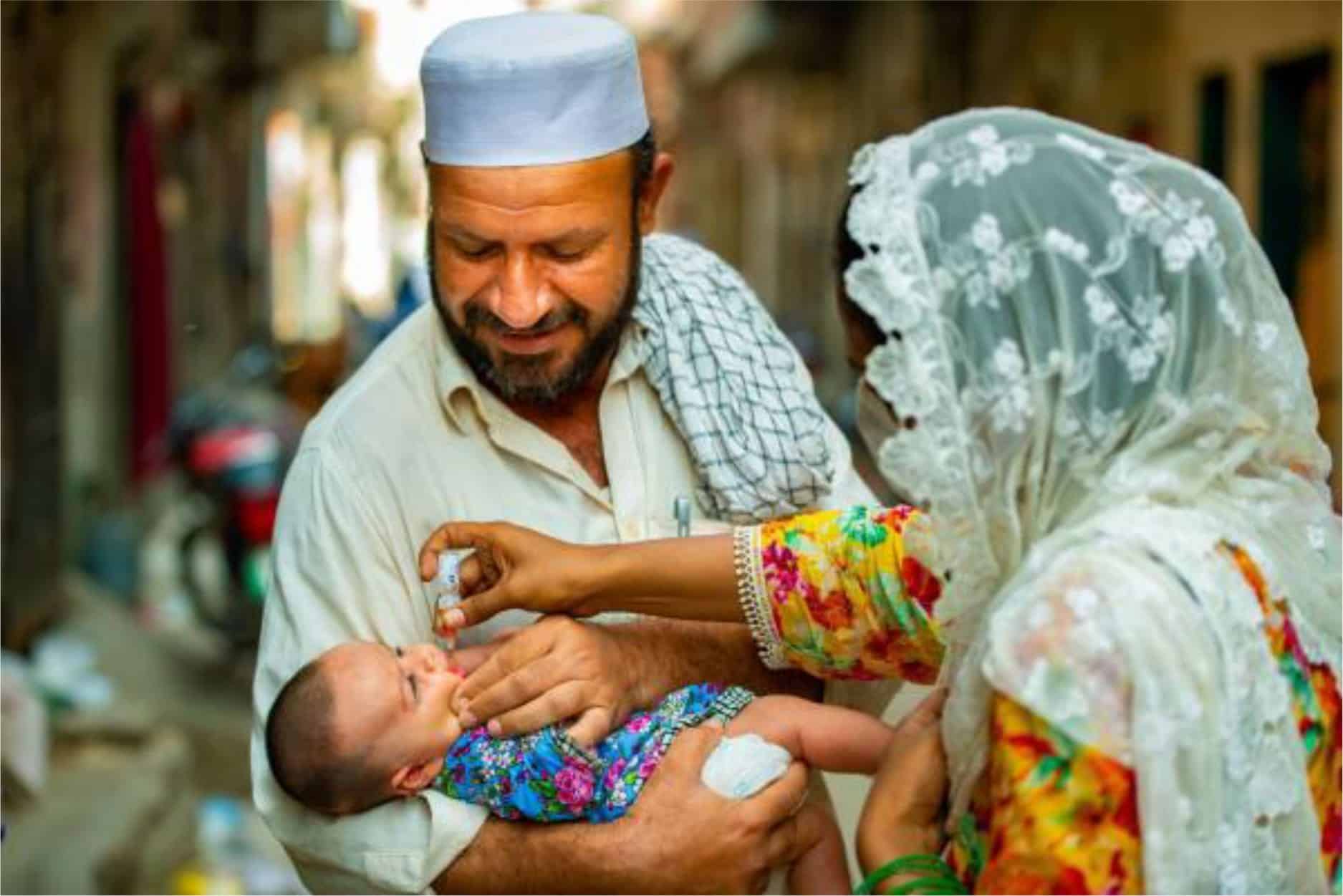 parent holds his child receiving the Oral Polio Vaccination in Pakistan